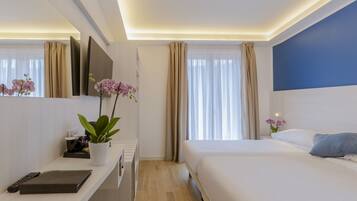Una habitación de hotel moderna con una cama grande, un escritorio con una computadora y una planta, un televisor de pantalla plana y un ventanal con cortinas.