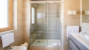 Un baño moderno con ducha envuelta en vidrio, un lavamanos y tocador con espejo.