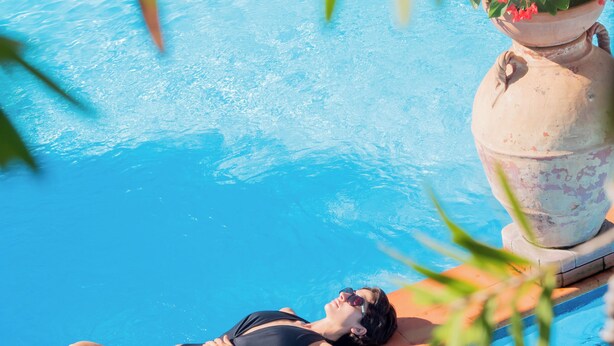 Une femme allongée sur une chaise longue au bord de la piscine.