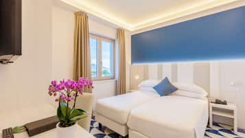 Habitación de hotel con cama, televisor, escritorio y un control remoto, además de una orquídea en maceta.