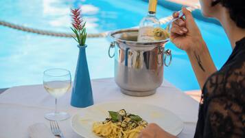 Une table à manger avec une assiette de pâtes, un verre à vin et une bouteille de champagne.