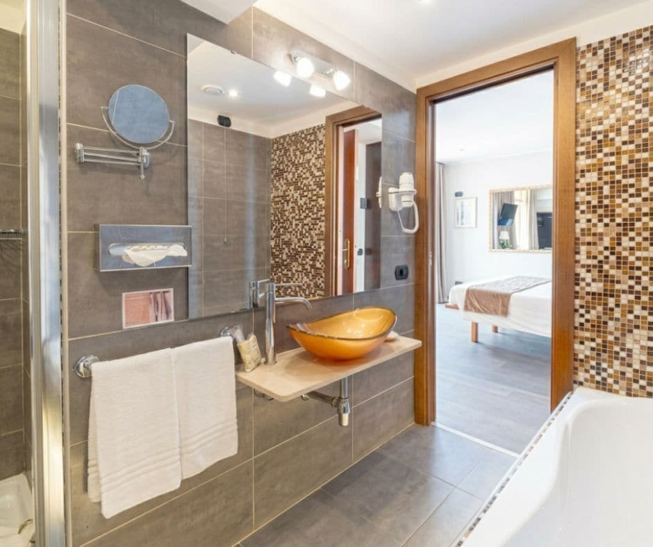 A modern bathroom with a large mirror, a vessel sink, and a shower area.