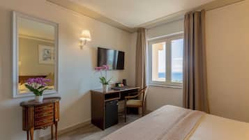 A hotel room with a bed, desk, chair, TV, and a window with curtains.