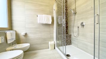 A modern bathroom with a glass-enclosed shower, a sink, and a toilet.