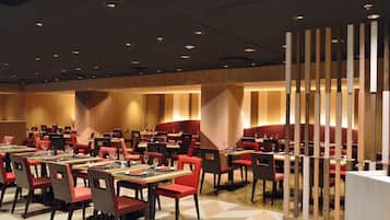A modern restaurant with multiple tables and booths, featuring geometric patterned flooring and warm lighting.