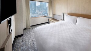 A hotel room with a large bed, a desk, a chair, a TV, and a window with a city view. - Shinjuku Prince Hotel (Tokyo)
