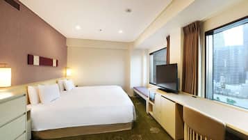 A hotel room with a large bed, a desk with a TV, a window with curtains, and a city view.