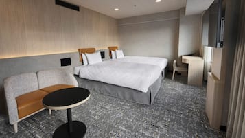 A modern hotel room with a large bed, a sofa, a small table, and a TV.