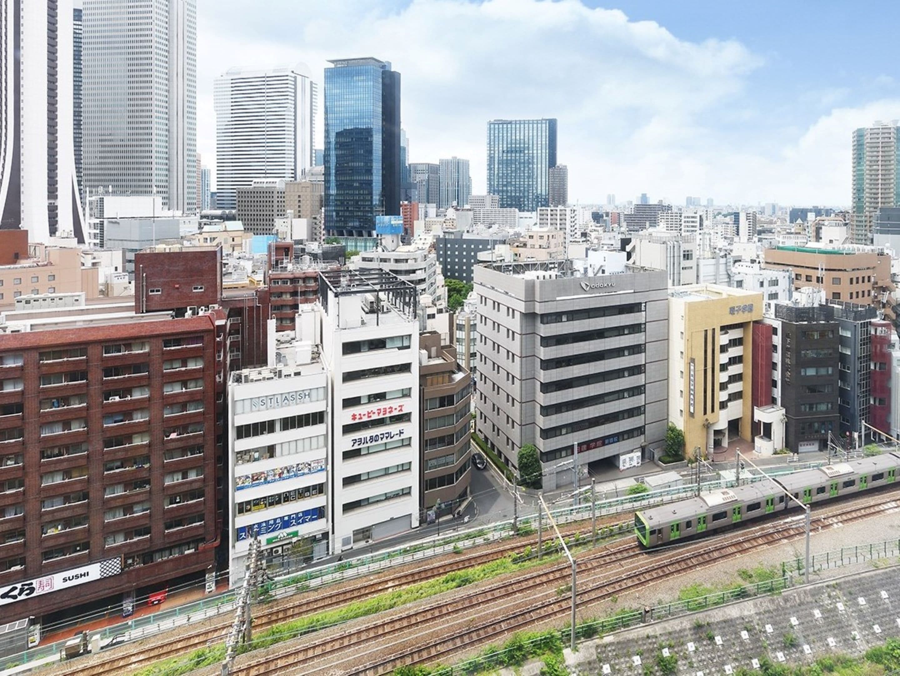 Un paisaje urbano con edificios modernos, un tren sobre rieles y un restaurante de sushi.