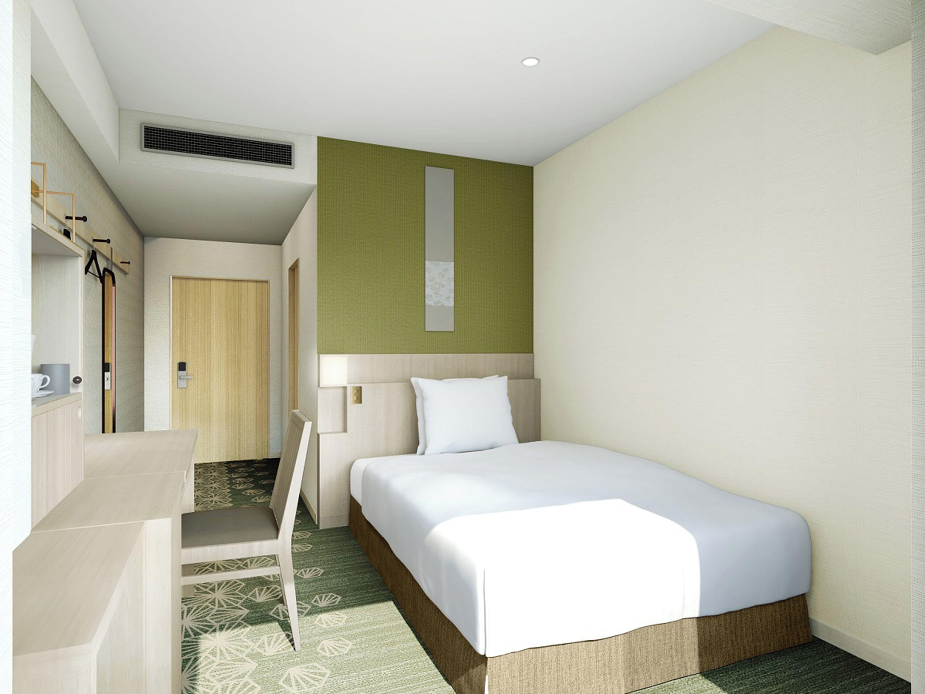 A modern hotel room with a single bed, a desk, and a chair.
