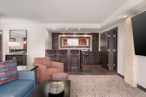 A hotel room with a seating area, a kitchenette, and a large mirror. - Garner Hotel Wadsworth by IHG (Wadsworth)