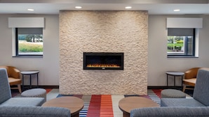 A modern lounge area with a stone wall fireplace, comfortable seating, and large windows offering views of the outdoors.