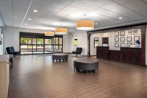 A spacious lobby with a reception desk, two black chairs, and a wooden floor. - Garner Hotel Wadsworth by IHG (Wadsworth)