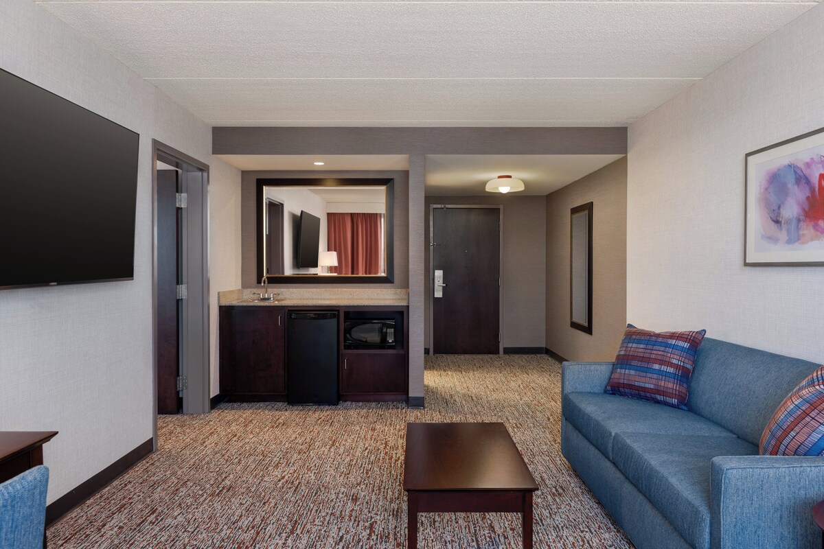 Une chambre d’hôtel équipée d’une kitchenette, d’un canapé, d’une table basse et d’un téléviseur à écran plat.