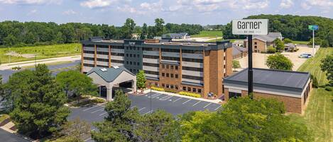 A multi-story hotel with a parking lot and a sign indicating it's by IHG.