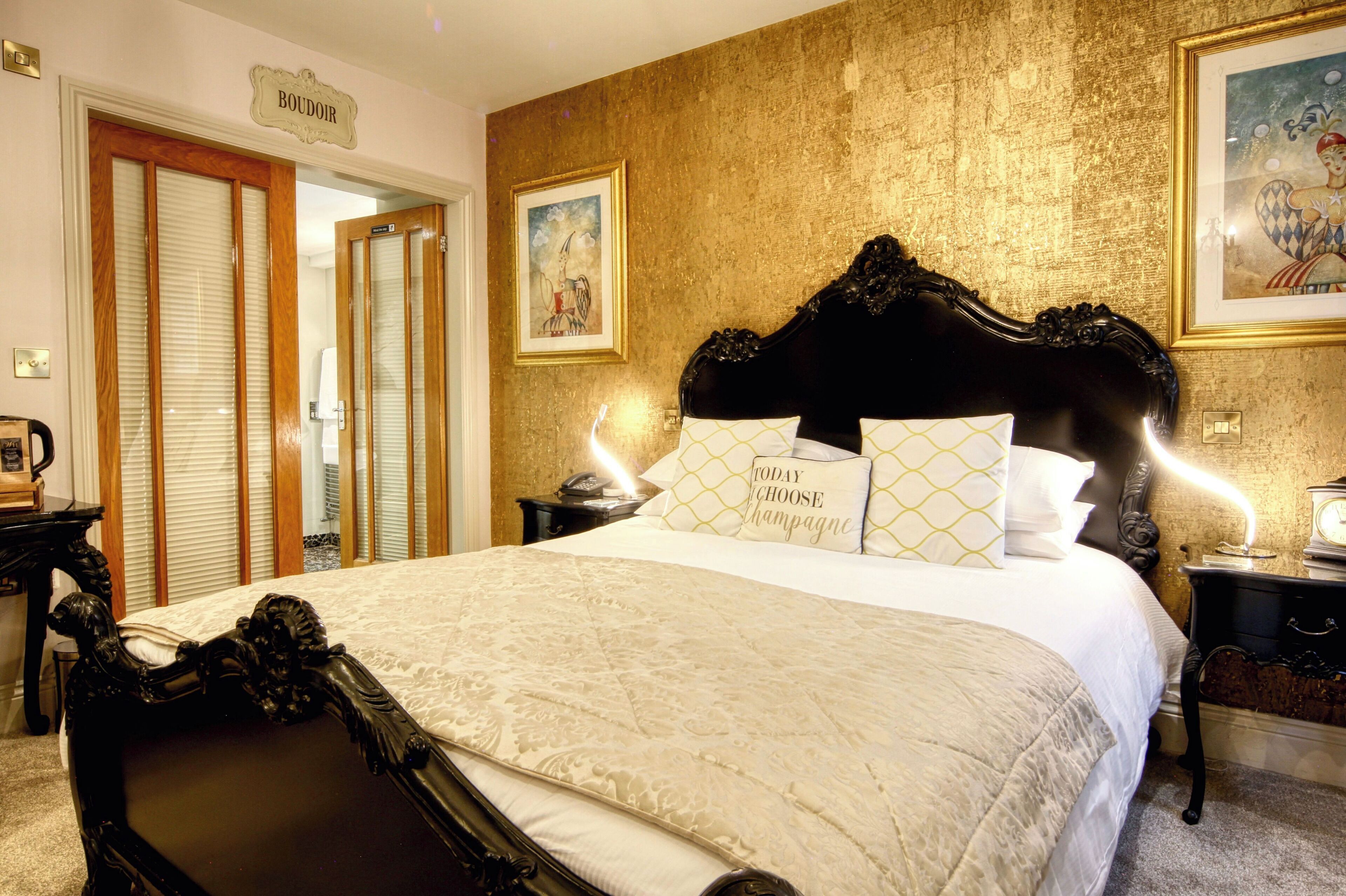 Un dormitorio lujoso con una cama grande, un cabecero ornamentado y una pared con textura dorada.