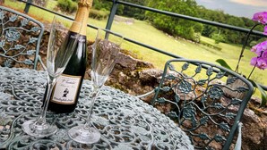 A bottle of champagne and a glass on a metal table with a scenic view in the background. - The Wensleydale Heifer (Leyburn)