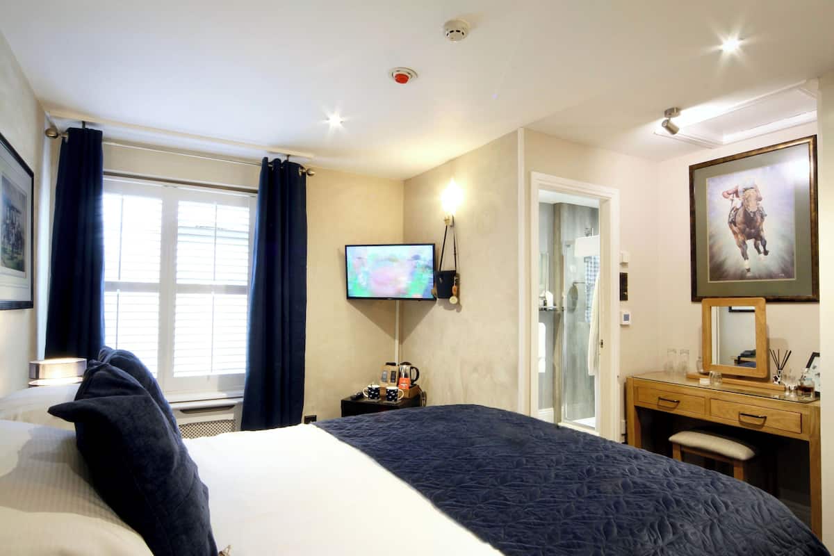A hotel room with a bed, a desk, a television, and a bathroom door.