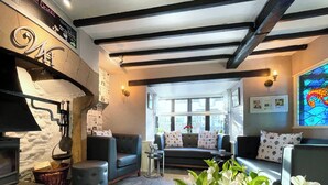 A cozy living room with a fireplace, comfortable seating, and a large window with a view. - The Wensleydale Heifer (Leyburn)