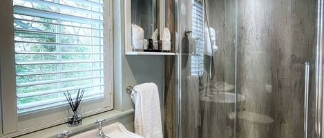 A bathroom with a sink, mirror, towel rack, and glass shower enclosure.