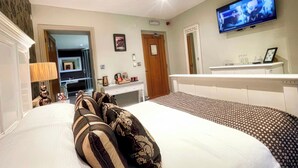 A hotel room with a bed, a desk, a television, and a bathroom visible through an open door. - The Wensleydale Heifer (Leyburn)