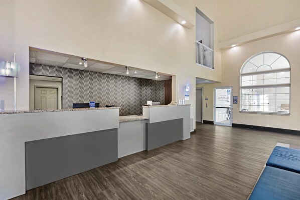 A reception area with a herringbone-patterned wall, a reception desk, and a large arched window.