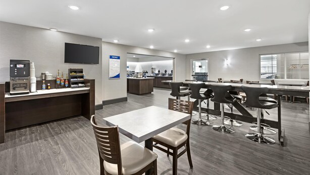 Un hall d’hôtel moderne comprenant un comptoir d’accueil, un espace salon et un bar.