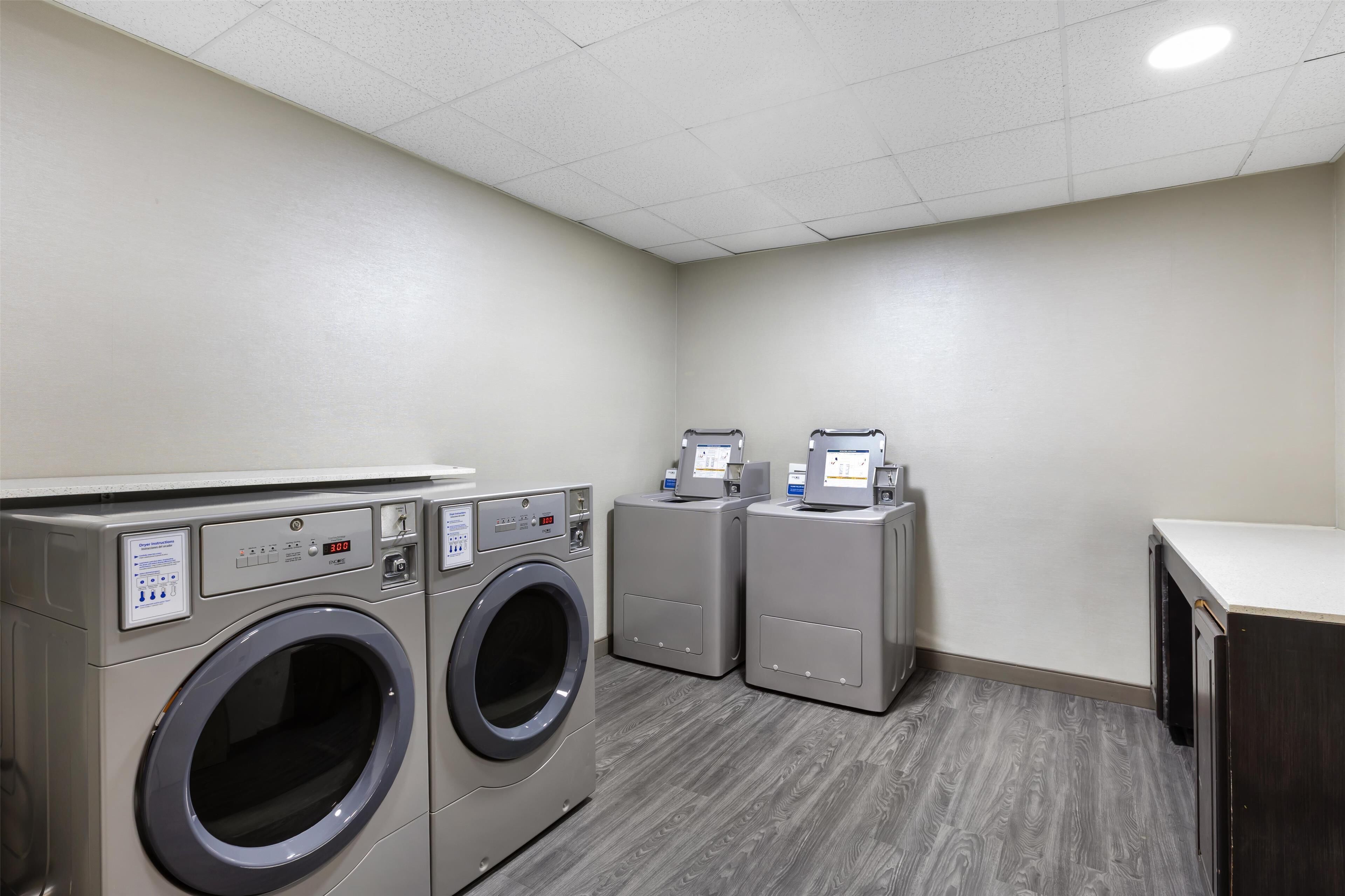 A laundry room with two front-loading washing machines and a dryer.