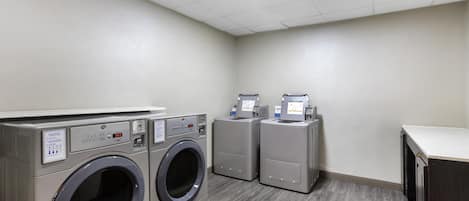 A laundry room with two front-loading washing machines and a dryer.