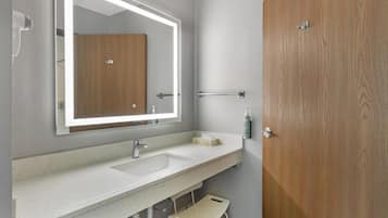 A modern bathroom with a large mirror, a sink, and a wooden door.