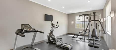 Un gimnasio moderno con cintas de correr, elípticas y máquinas de pesas.
