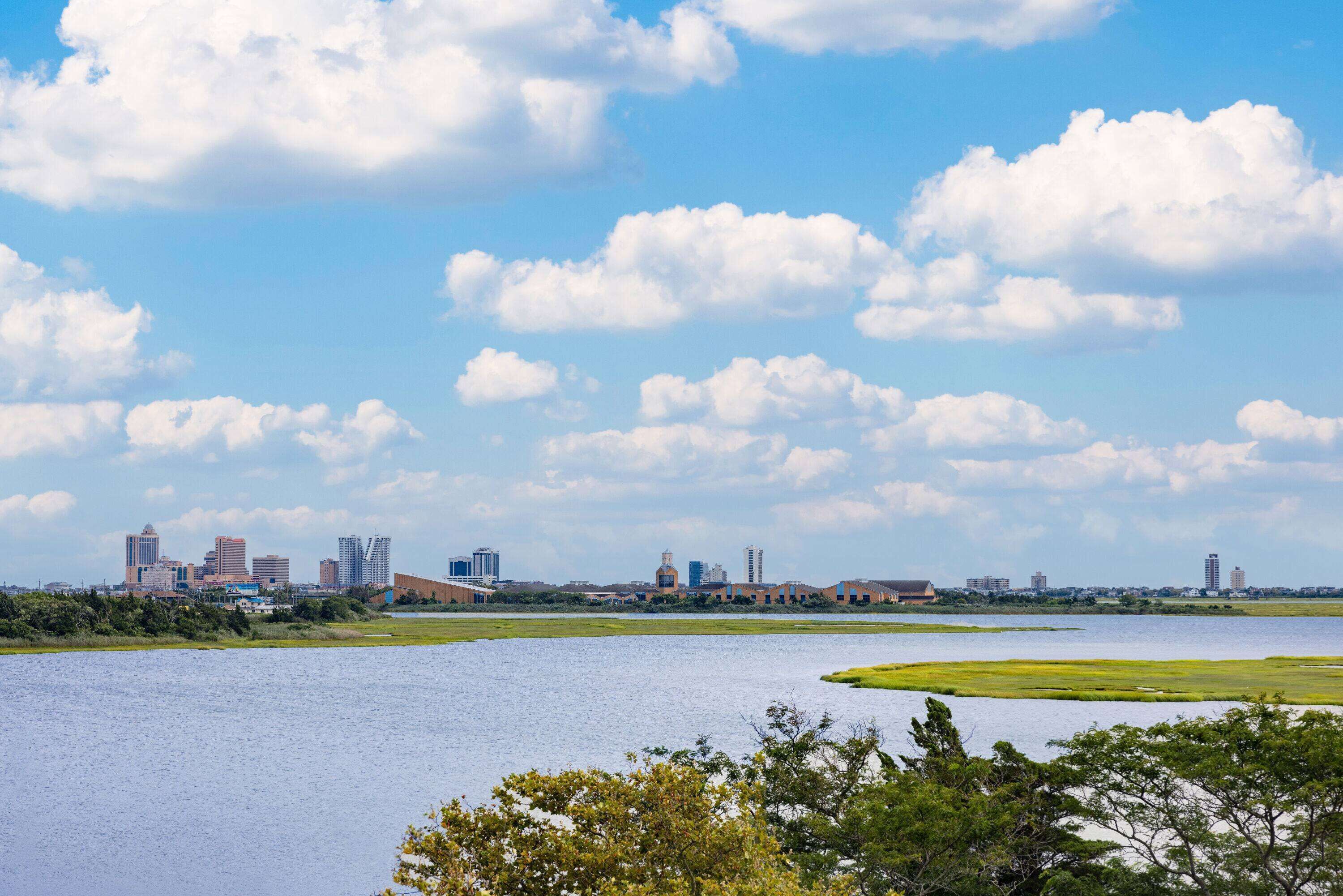 A city skyline with modern buildings and a large body of water in the foreground.