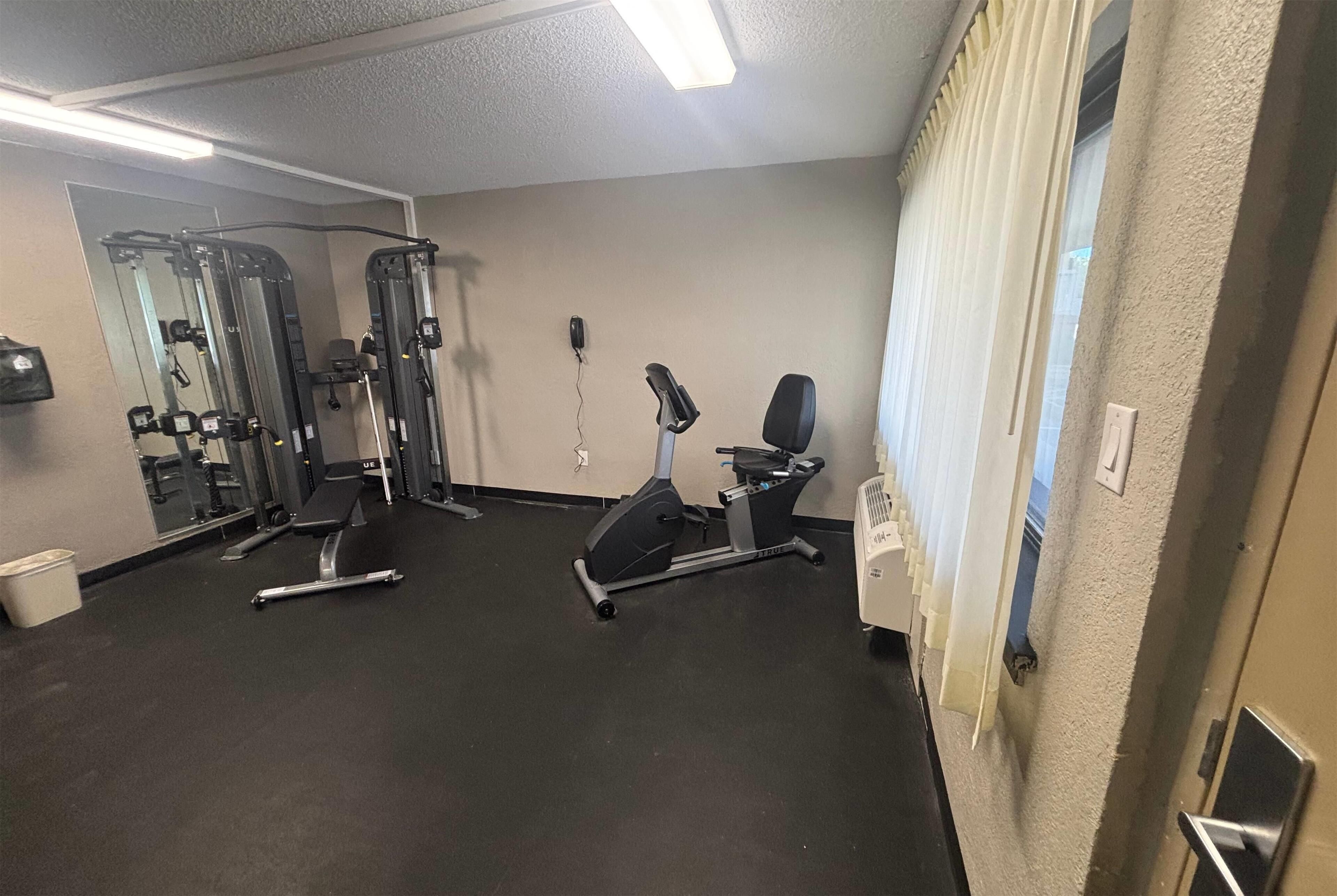 A gym with exercise equipment, a mirror, and a door.