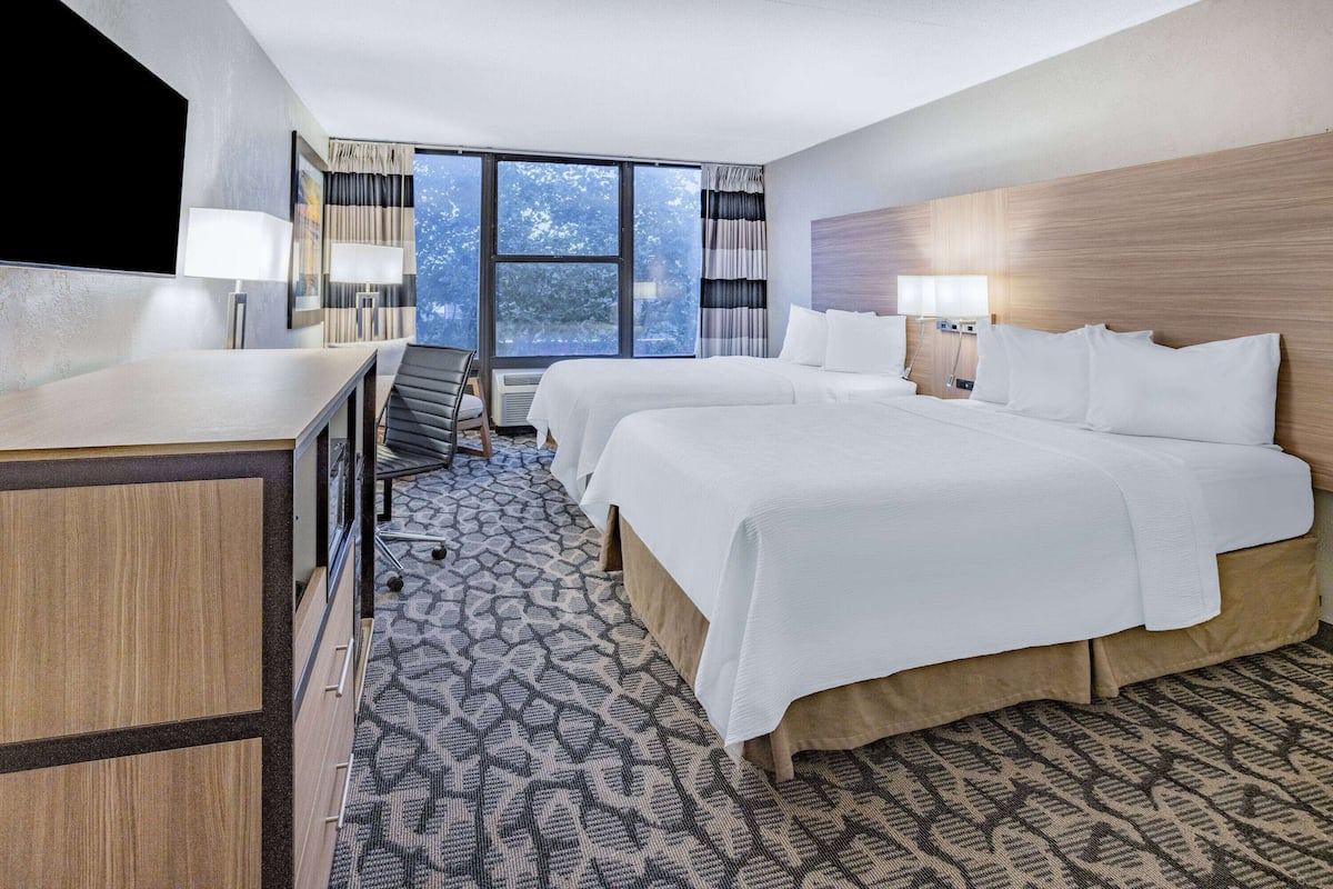 A hotel room with a large bed, a desk, and a TV.