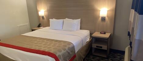 A hotel room with a bed, two bedside lamps, a nightstand, and a clock.