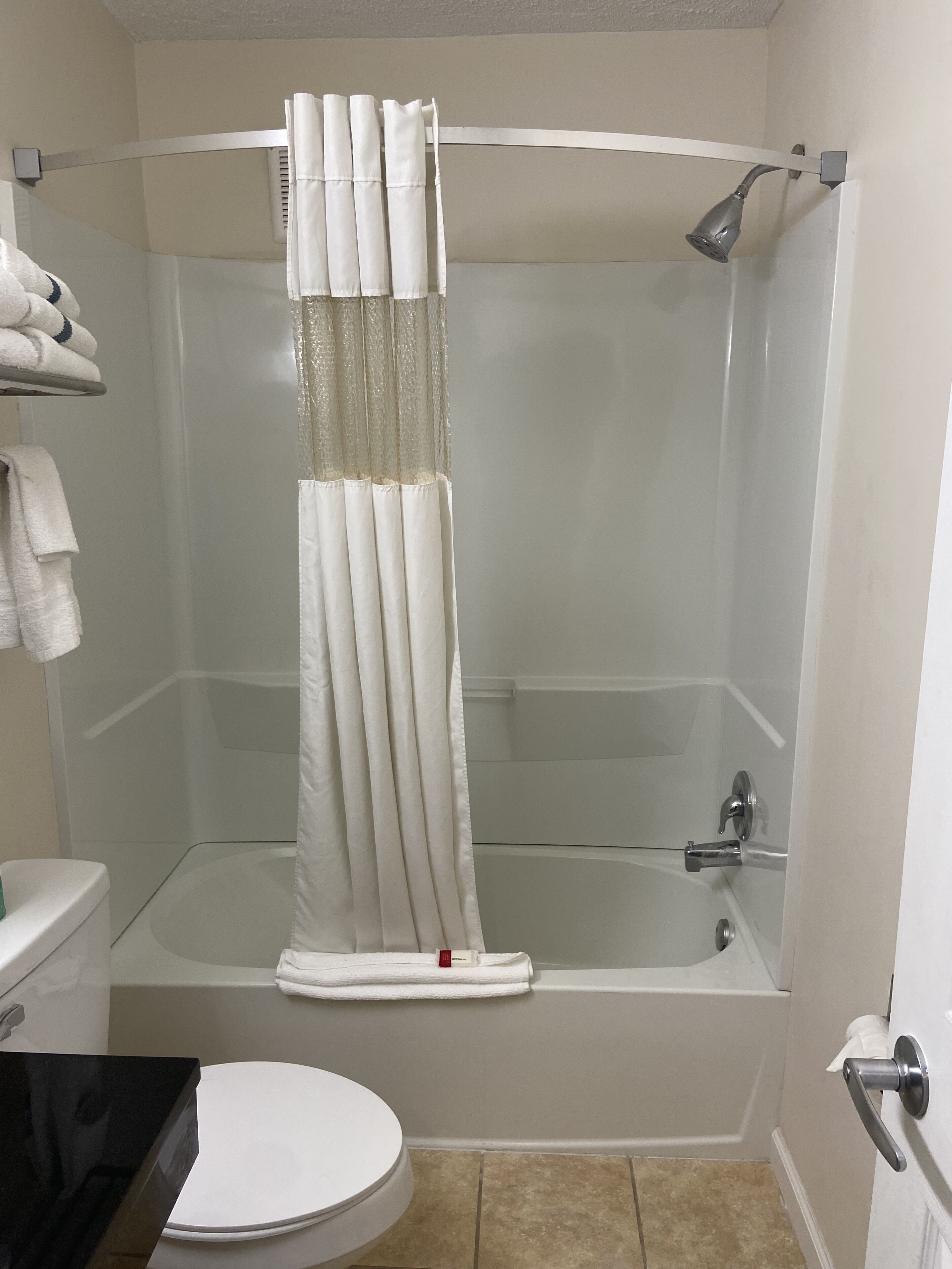 Un baño con bañera, inodoro y cortina de ducha.