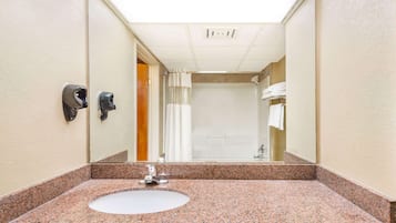 A bathroom with a granite countertop sink, a mirror, a towel rack, and a shower with a curtain.