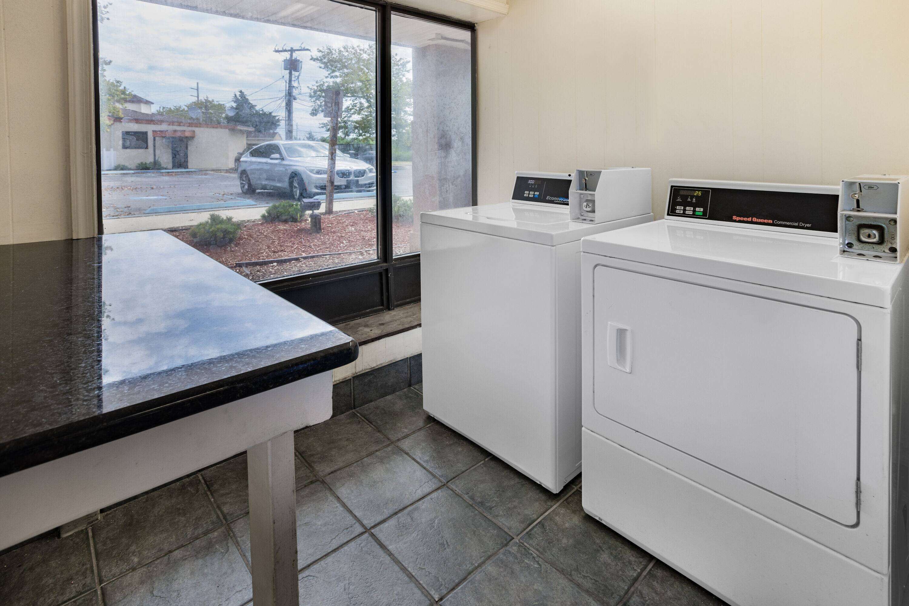 A laundry area with a washing machine and dryer, a window with a view of a parking lot and a building, and a countertop.