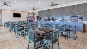 Un restaurante con varias mesas y sillas, un muro de ladrillo y una barra con diversos artículos.