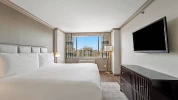 A hotel room with a large bed, a flat-screen TV, a desk, and a window with a city view.