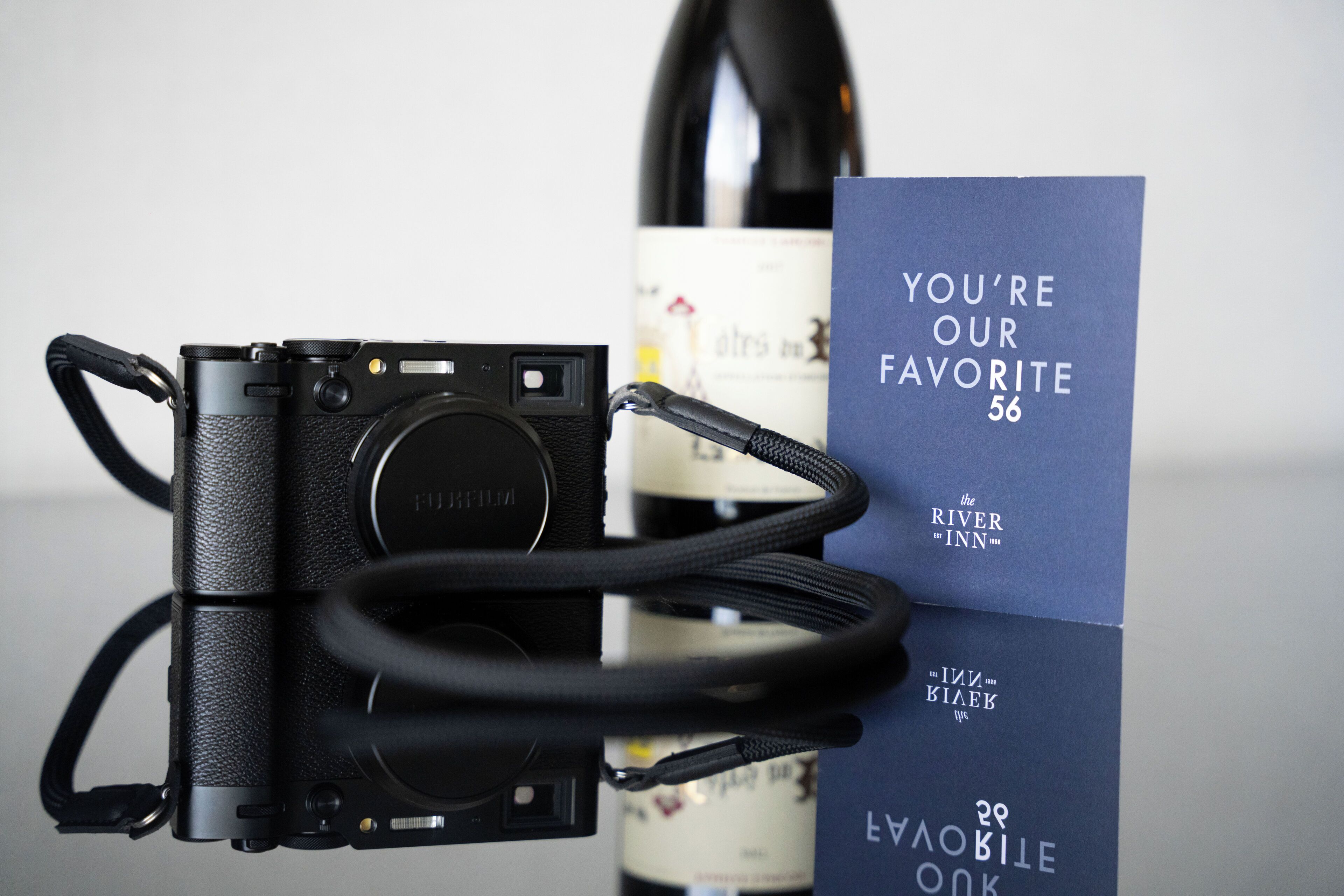 A camera, a wine bottle, and a card with text.