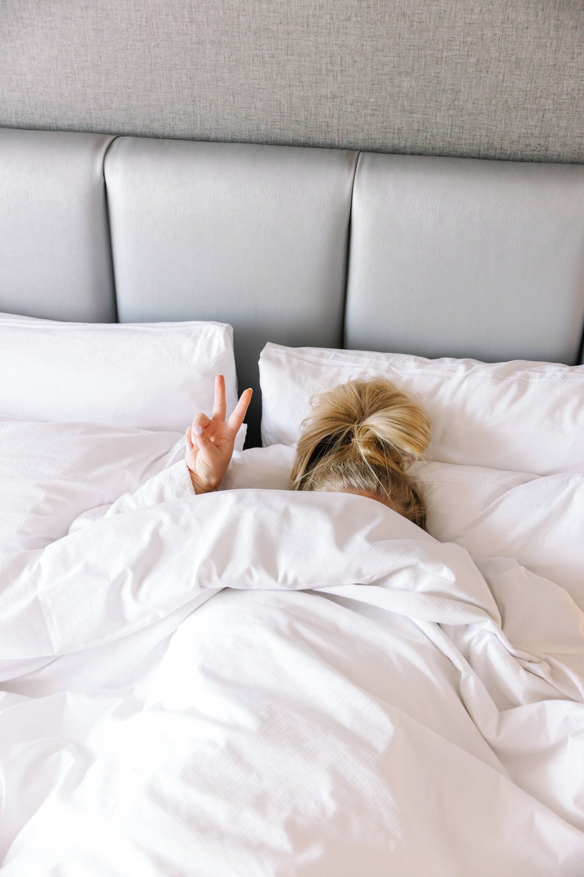 A bed with white bedding and a grey headboard.