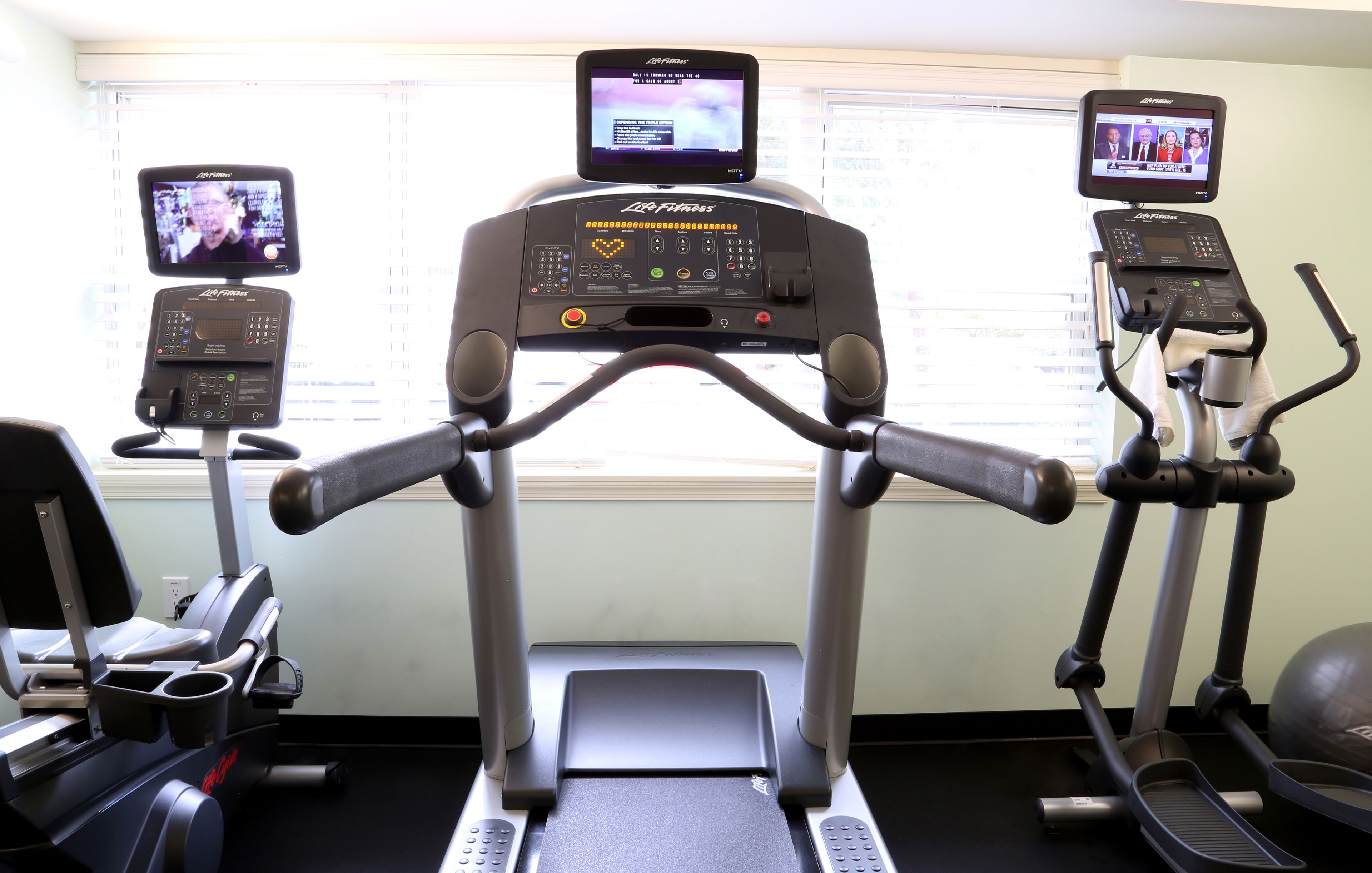 Un gimnasio con cintas de correr, una bicicleta estática y una máquina de remo.