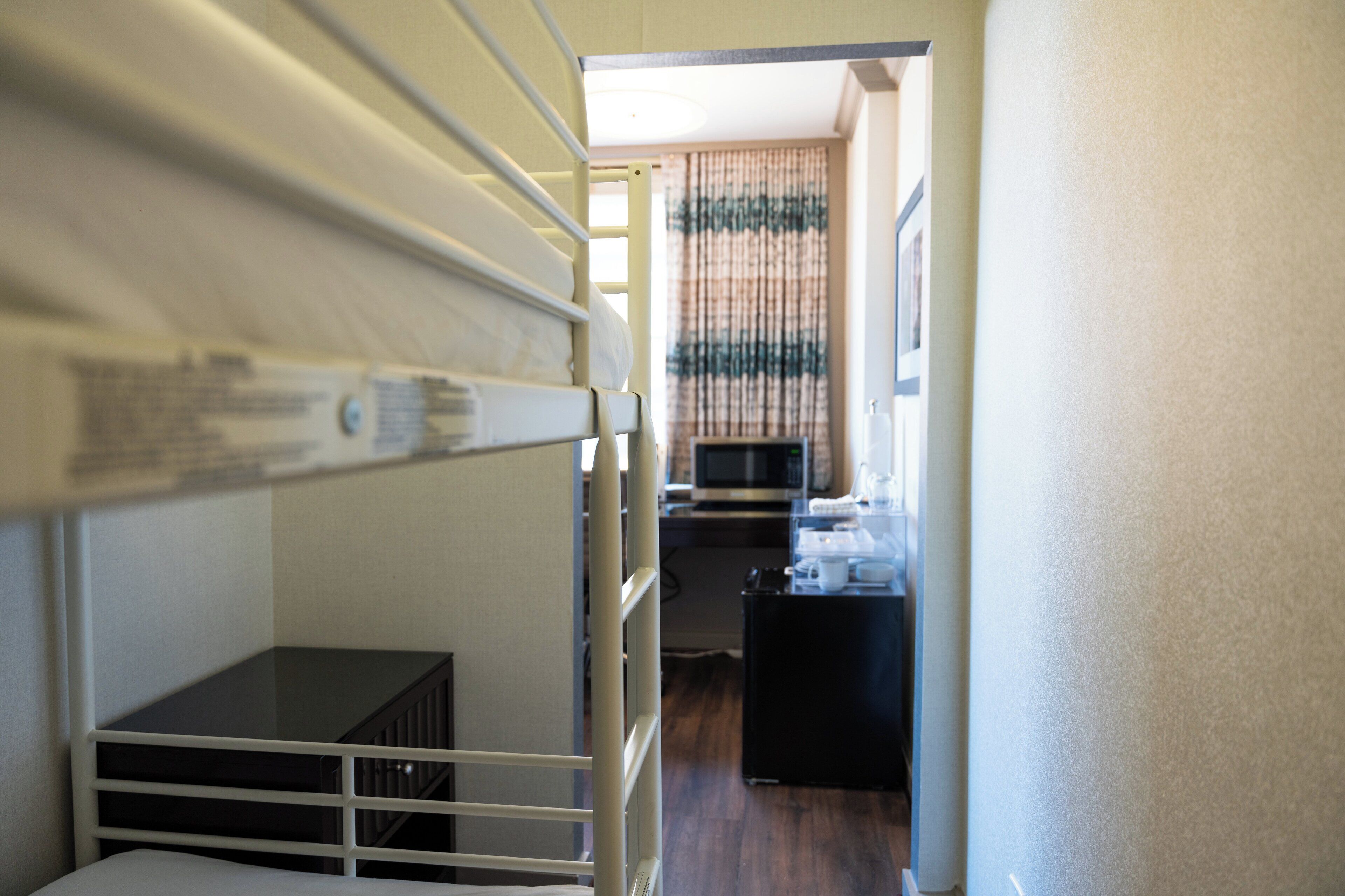 A bunk bed room with a desk and a microwave.