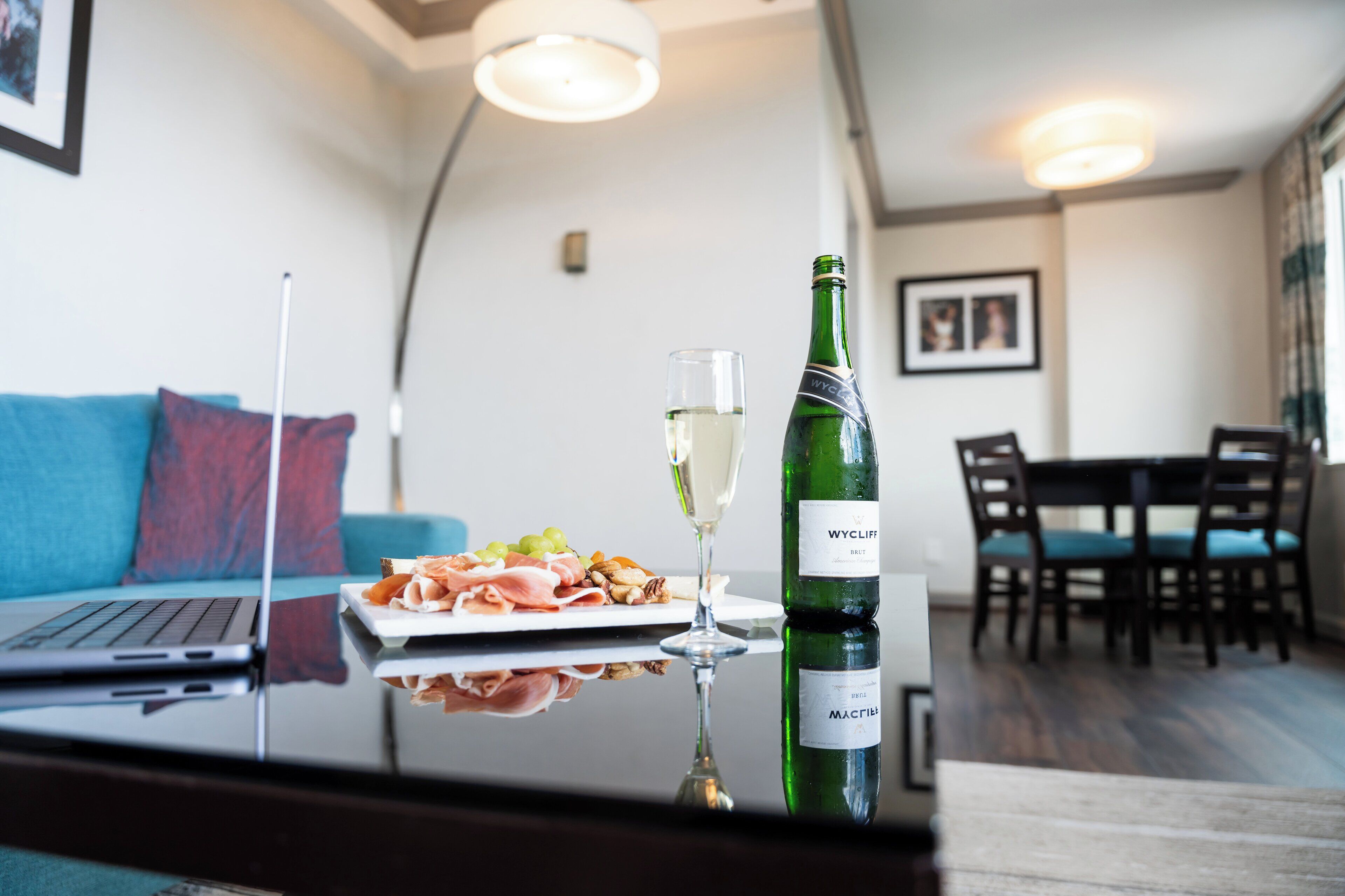 Una mesa de comedor con una botella de vino, una copa de vino y un plato de comida.