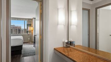 A hotel room with a bed, a bathroom with a granite countertop, and a large mirror.