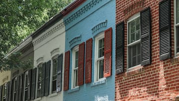 Una hilera de casas de pueblo coloridas con fachadas rojas, blancas y azules, contraventanas negras y un farol.