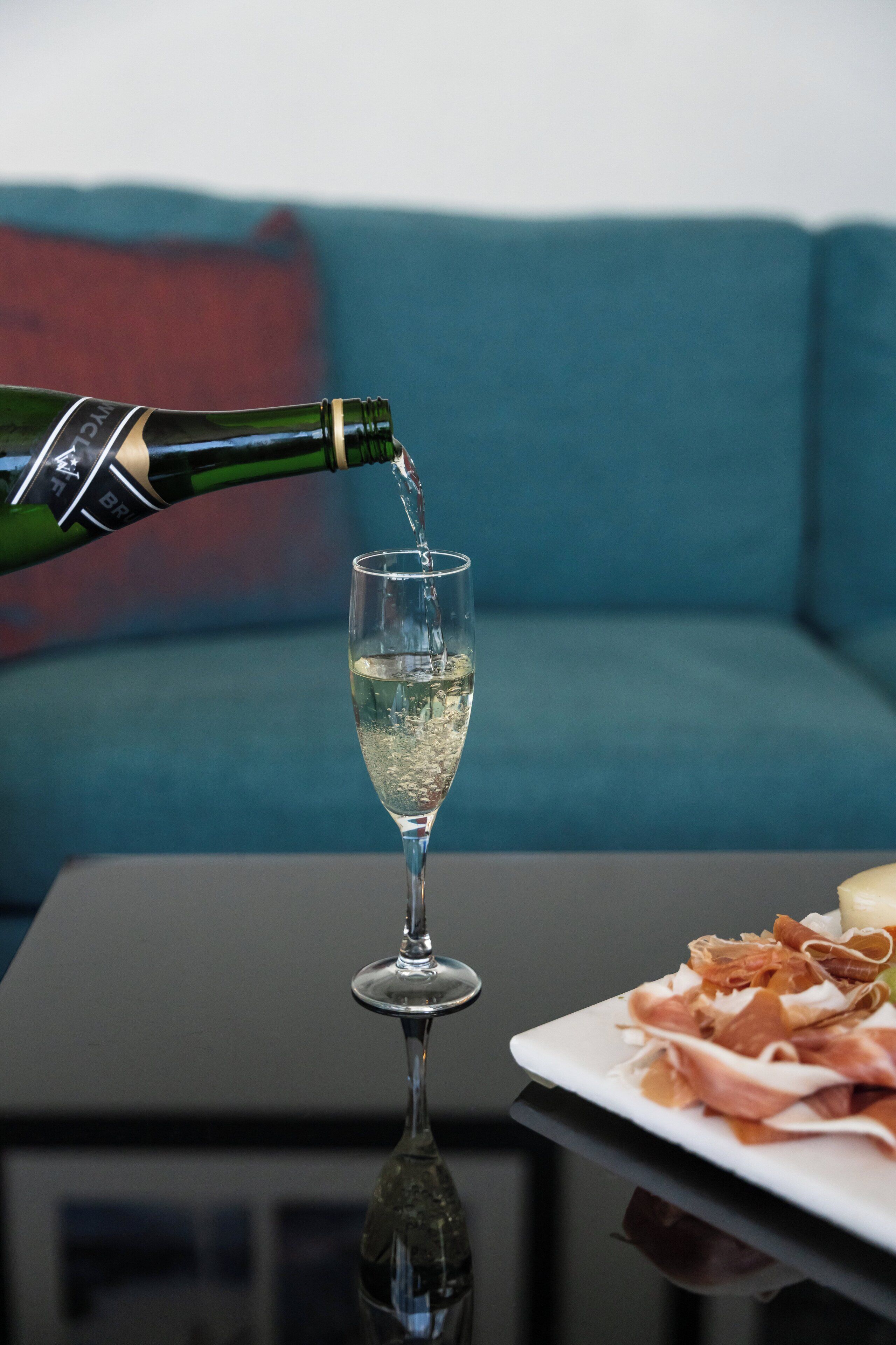 A glass of champagne being poured into a stemmed glass on a table.