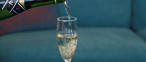 A glass of champagne being poured into a stemmed glass on a table.
