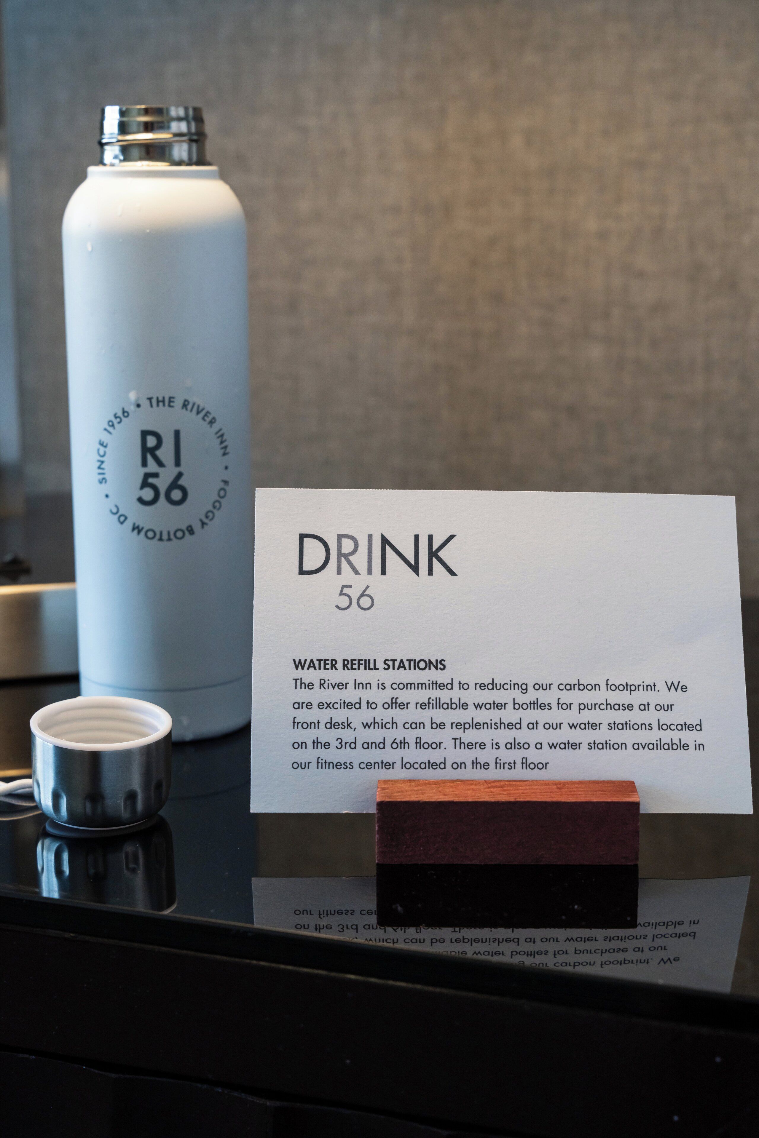 A water bottle labeled "R1 56" and a sign indicating "DRINK 56" with information about water refill stations at The River Inn.